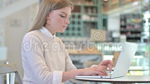 令人震惊的年轻女子在咖啡馆里用笔记本电脑视频的预览图