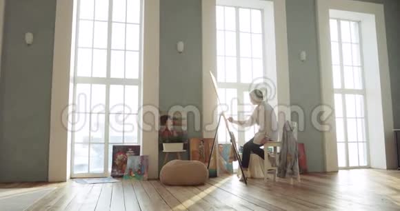 画画师坐在靠近窗户的艺术工作室里镜头放大视频的预览图