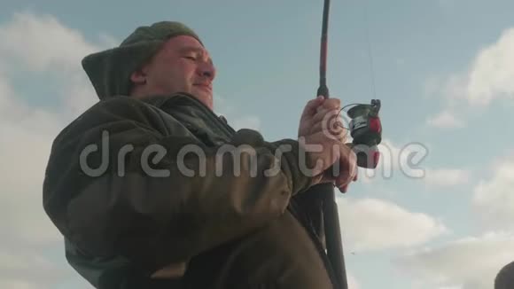 船上的白渔夫在捞鱼时把鱼从水里捞出来美丽的天空在背景上低角度视角视频的预览图
