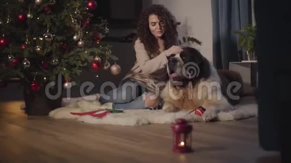 除夕夜带着宠物坐在家里微笑的白种人女孩的肖像灯笼上挂着蜡烛视频的预览图