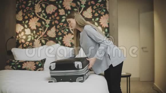 可爱的女人在酒店房间打开行李一位女士打开手提箱视频的预览图