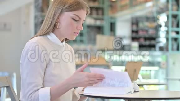 在咖啡馆读书的年轻女性视频的预览图