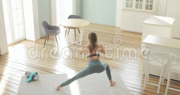 运动的年轻女子在家中进行侧击训练为滑翔做深蹲视频的预览图