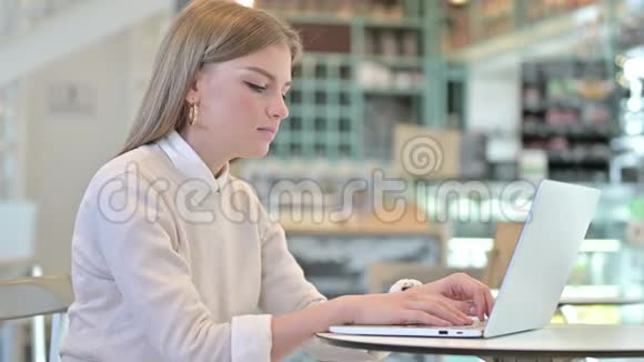 在咖啡馆工作的背痛的年轻女人视频的预览图