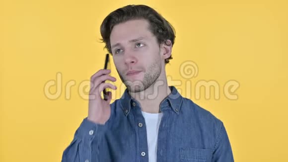 黄色背景下的年轻人在智能手机上讲话的肖像视频的预览图
