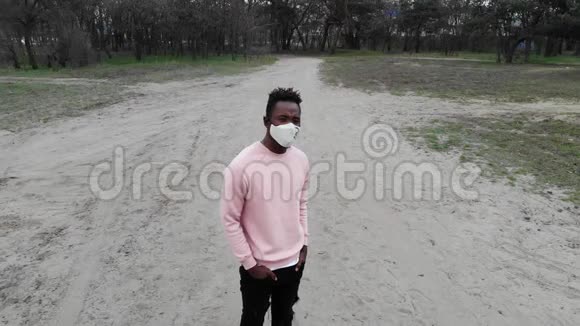 一个年轻的非洲男子站在森林小路上脸上戴着医疗保护面罩视频的预览图