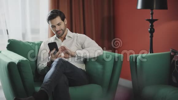 年轻的商人看着豪华酒店的移动商务男士放松电话视频的预览图