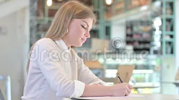 一个认真的年轻女人在咖啡馆做文书工作视频的预览图