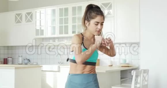 运动健康的女人正在做腹肌练习在家里的厨房里站着视频的预览图