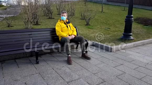 坐在公园长椅上的病人戴着医疗面具视频的预览图