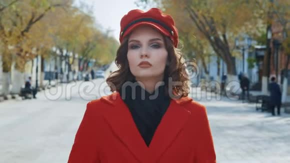 肖像年轻优雅的少女模特在秋天的城市拍照穿着红色外套看电影视频的预览图