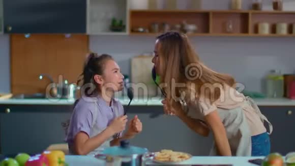 有趣的女孩和女人在现代厨房里用勺子慢动作唱歌视频的预览图