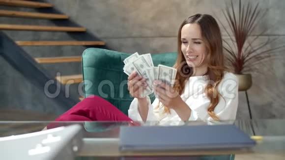 快乐的女孩在办公室里数钱领取现金薪金的女商人视频的预览图
