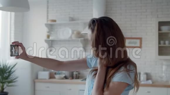开朗的女人在厨房对着手机摄像头眨眼女孩自拍照片视频的预览图