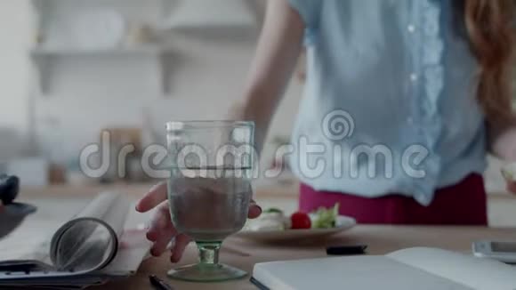 漂亮的女人在白色厨房里通过耳机说话女孩喝水视频的预览图