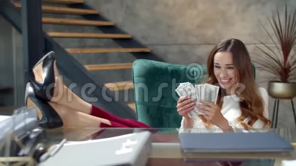 快乐的女商人拿着钱腿在桌子上赚钱的女孩下雨了视频的预览图