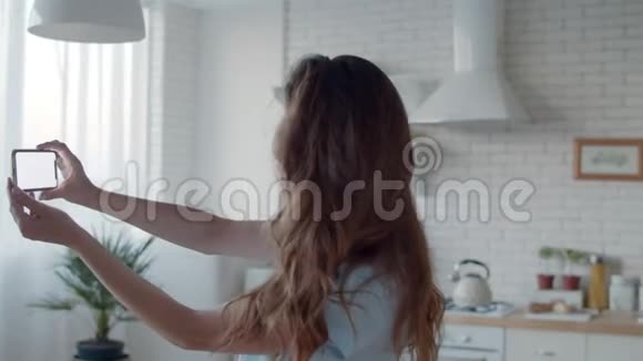 漂亮的女孩在厨房内部摆姿势给摄像头打电话女人在自拍视频的预览图