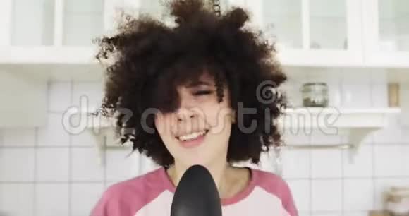 用勺子作为麦克风在厨房唱歌的年轻女孩的肖像视频的预览图
