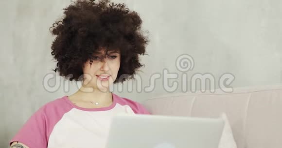 年轻女性自由职业者的肖像卷发在笔记本电脑上工作视频的预览图