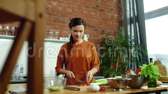 女人在砧板上切番茄女孩在沙拉碗里扔蔬菜视频的预览图