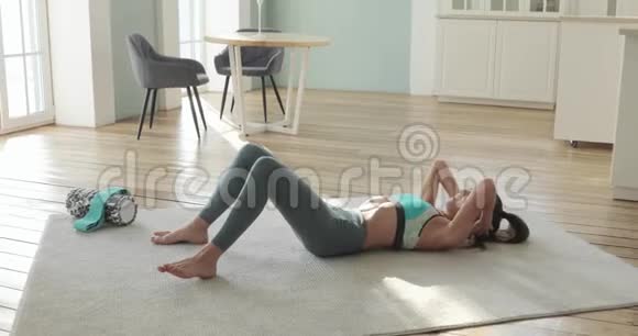 运动健康的女人正在做腹肌练习在家里的地板上侧视视频的预览图