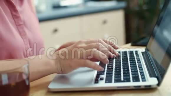 女商人在家里做笔记本电脑微笑的女孩在厨房喝茶视频的预览图