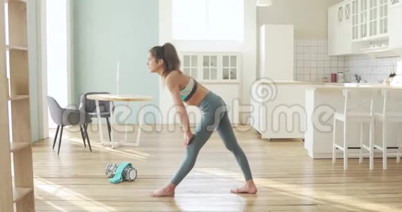 运动的年轻女人在家里做伸展腿的瑜伽姿势视频的预览图