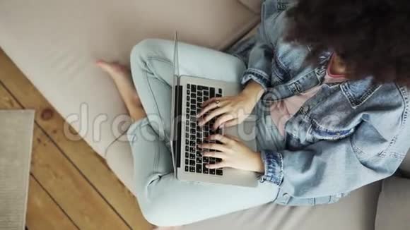 女人正在写打字坐在沙发上的笔记本电脑俯视视频的预览图