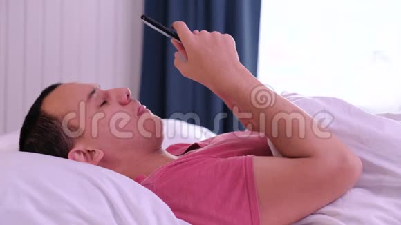 早上躺在床上的男人看电话手机掉在脸上视频的预览图
