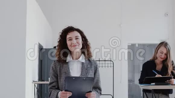 快乐美丽的白种人商务女性卷发走在办公室微笑相机慢动作红色EPIC视频的预览图