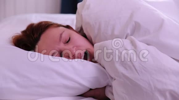 红发的年轻女子早上在床上打哈欠视频的预览图
