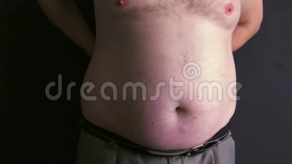 一个光着肚皮的胖子用卷尺测量他的腹部视频的预览图