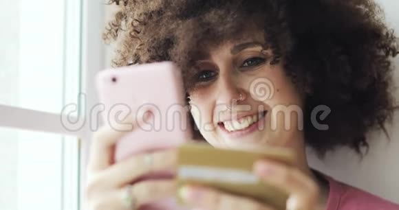 幸福女人的肖像正在使用智能手机制作在线支付银行卡视频的预览图