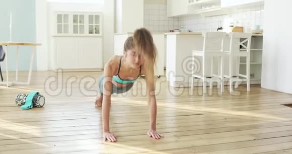 女子练习向上和向下面对狗姿势在瑜伽运动在家里视频的预览图