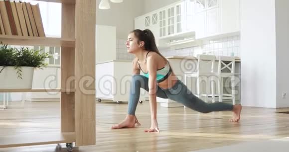 运动的年轻女人正在家里的客厅里做运动使身体变暖视频的预览图