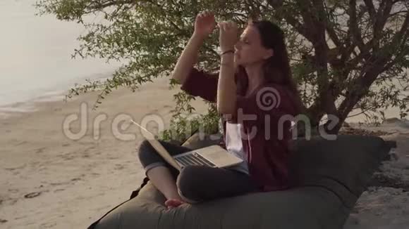 带着笔记本电脑在热带海滩工作的女孩视频的预览图