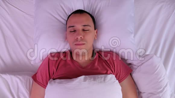 俯视图年轻人睡在白色的枕头上视频的预览图