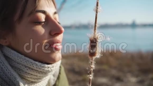 迷人的年轻女人吹在芦苇的干锥上视频的预览图