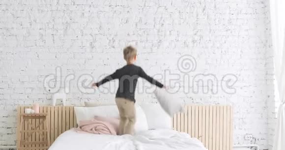快乐的小男孩在玩耍在床上跳跃在托儿所里转过身视频的预览图