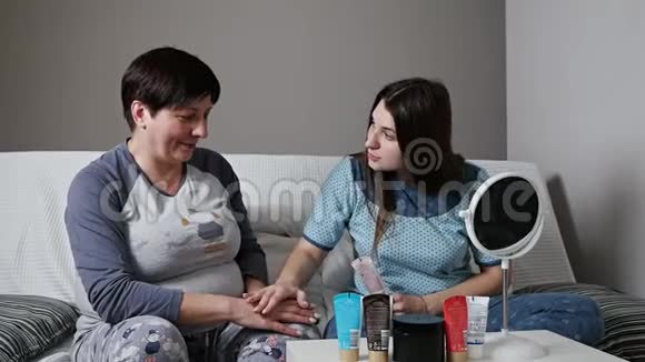 一个年轻的女人在家里把奶油涂在她的手上家庭皮肤护理视频的预览图