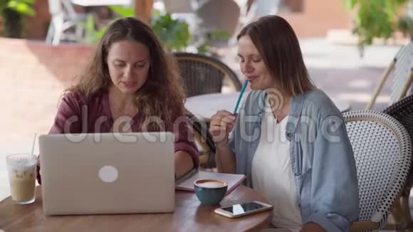 快乐的女性朋友一起在户外咖啡馆工作视频的预览图