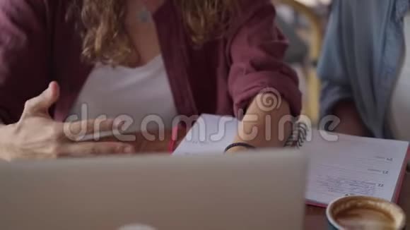 在户外咖啡厅与笔记本电脑合作的快乐女性朋友特写视频的预览图