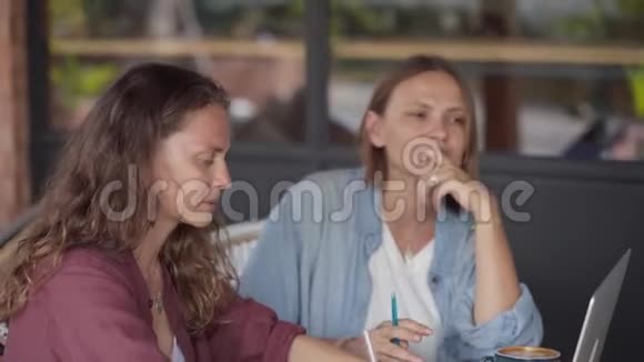 快乐的女性朋友一起在户外咖啡馆工作视频的预览图