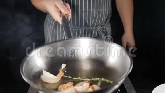 餐厅厨房概念厨师在黑色背景的煎锅中煎虾厨师投掷混合和视频的预览图