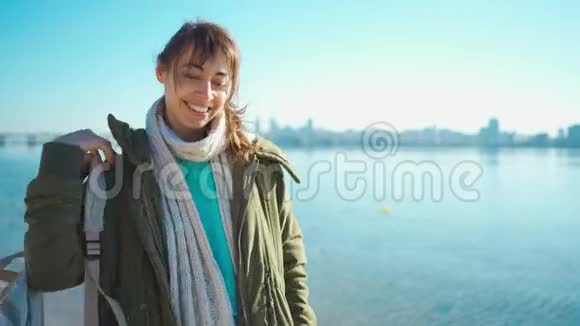 迷人的微笑年轻的黑发女人穿上小帆布背包在海滩上散步视频的预览图