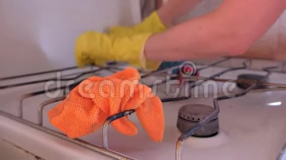 女人手戴黄色橡胶手套在厨房洗脏煤气炉视频的预览图