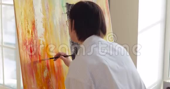 女画师用画笔在画架上画多色画视频的预览图
