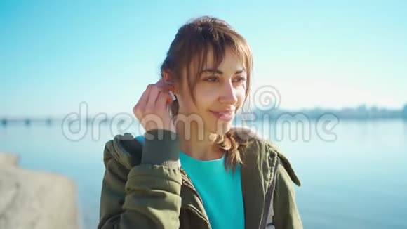 迷人的女人插入耳朵无线耳机做双重点击和微笑看起来平静和自信视频的预览图