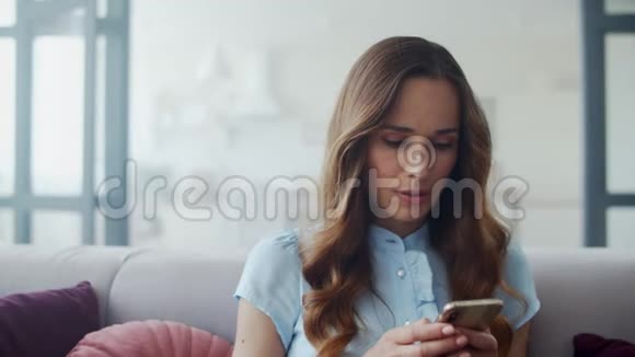 商务女性在沙发上通过电话阅读好消息女孩在电话里聊天视频的预览图