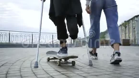 一条腿拄着拐杖的年轻人骑着滑板和他的女朋友一起散步残疾人的积极生活这就是视频的预览图